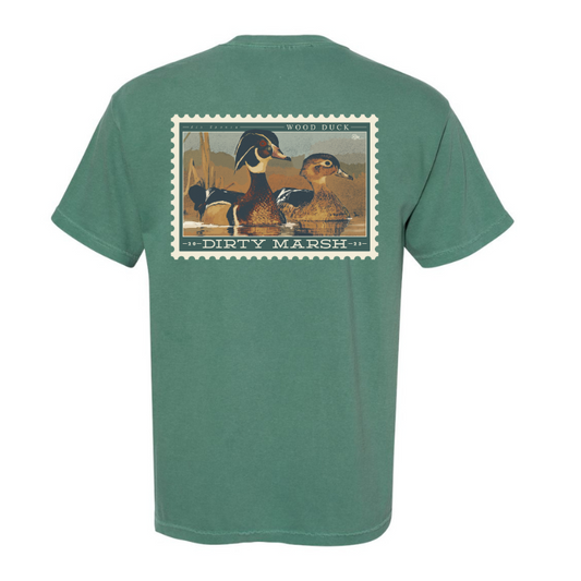 A Comfort Colors Wood Duck Stamp Tee in Light Green that says Dirty Marsh.