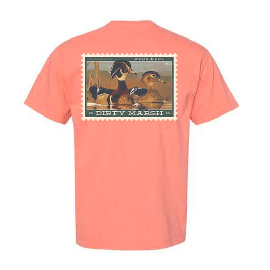 A Comfort Colors Wood Duck Stamp Tee in Teracotta that says Dirty Marsh